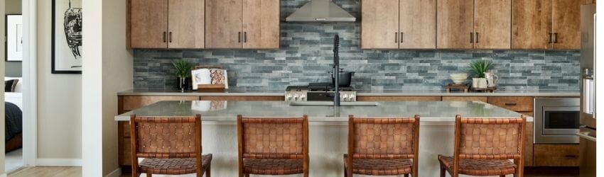 Modern kitchen with wooden cabinets and four woven chairs.