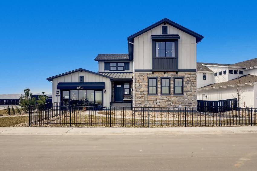 Modern two-story house with stone facade and fence.