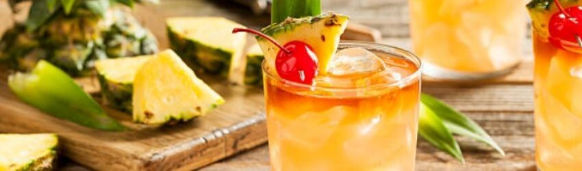 Tropical cocktails garnished with pineapple and cherry.