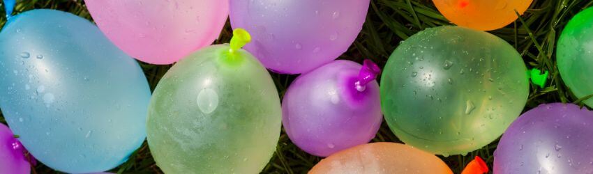 Colorful water balloons scattered on green grass.