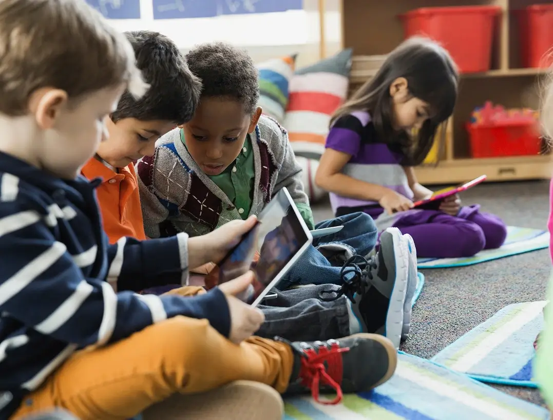 Children using tablets and learning together in a modern classroom environment