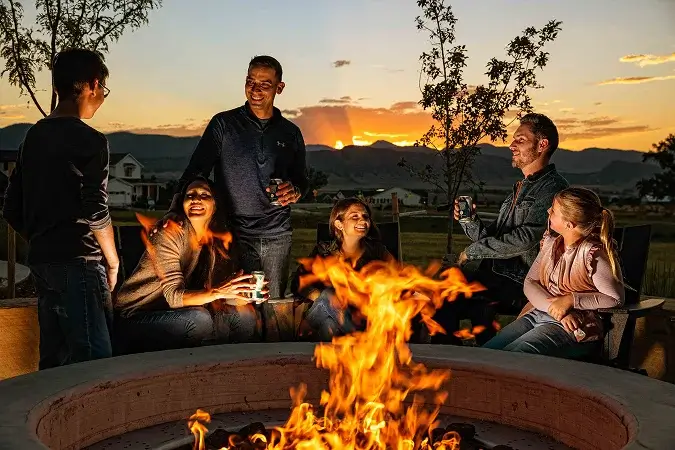 Residents gathering around a community firepit with Front Range mountain sunset views