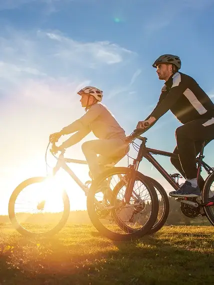 Couple riding bicycles outdoors during sunset