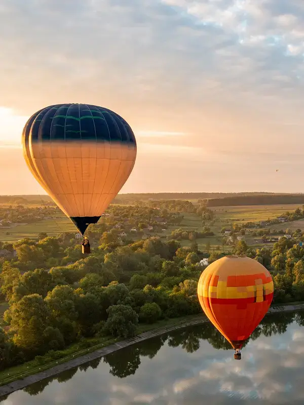 Hot air balloons flying over countryside during sunset