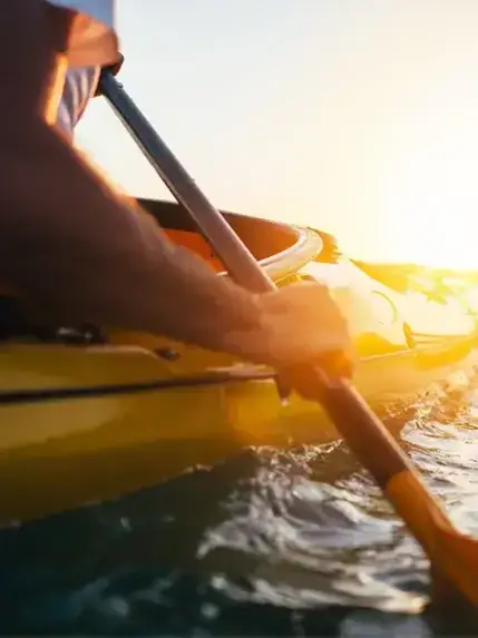 Close-up of person kayaking on water during sunset