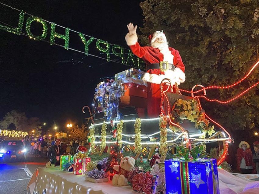 Santa waving from a decorated holiday parade float.