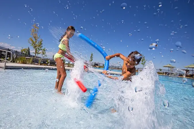 Children playing in the resort-style community pool at Solstice on a sunny day