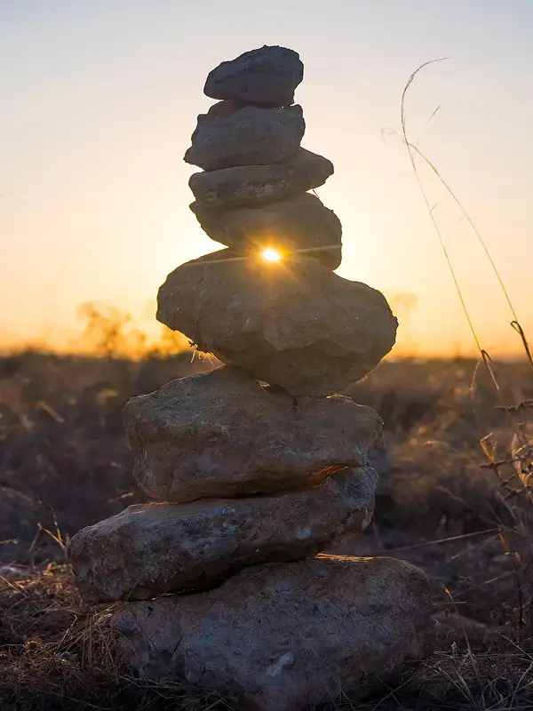 Balanced stacked stones with sunlight shining through at sunset