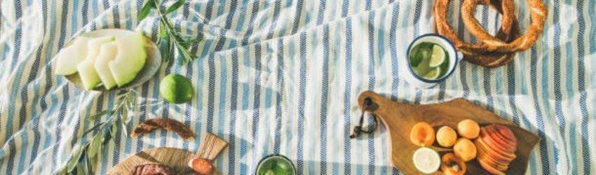 Striped picnic blanket with fruits and pretzels.
