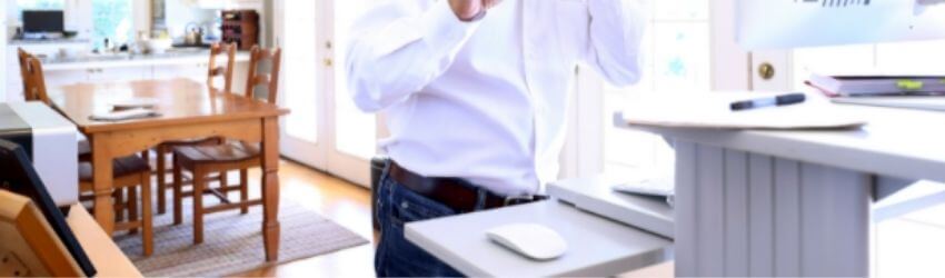 Person working at standing desk in bright kitchen.
