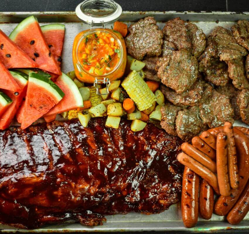 Barbecue spread with ribs, hotdogs, burgers, and watermelon.