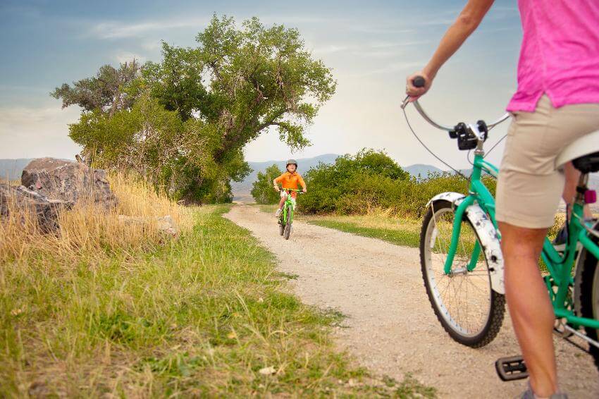 Child biking on dirt path in lush surroundings.