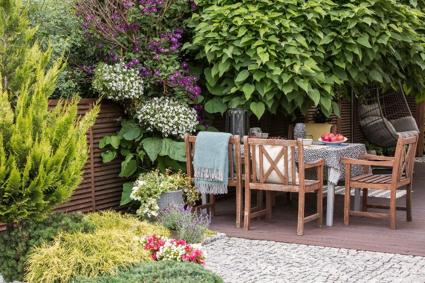 Outdoor patio set surrounded by lush green plants.
