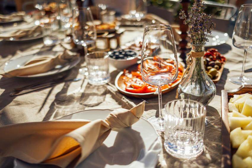 Elegant outdoor table setting with food and wine glasses.