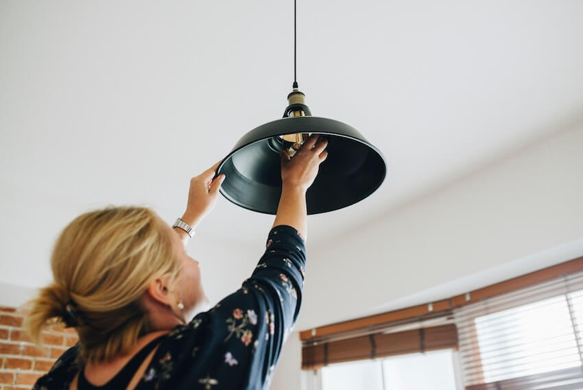 Person adjusting ceiling light fixture in a room.