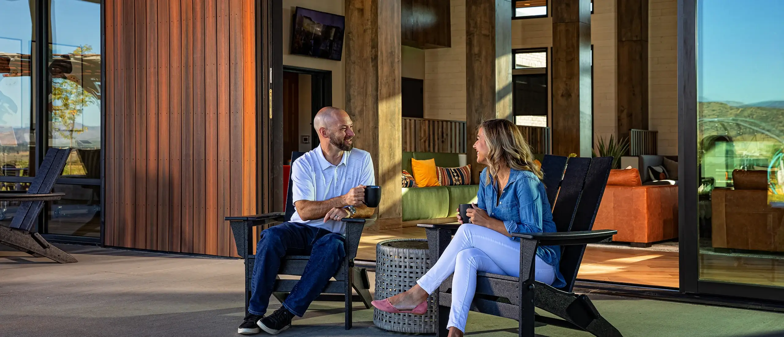 Two people enjoying coffee on patio chairs.