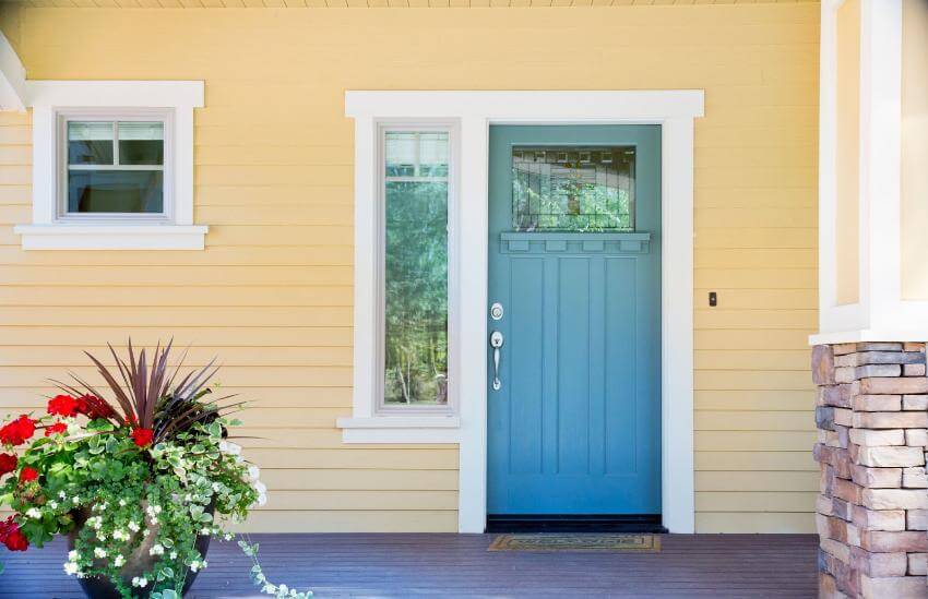 Blue door on yellow house with flower pot.