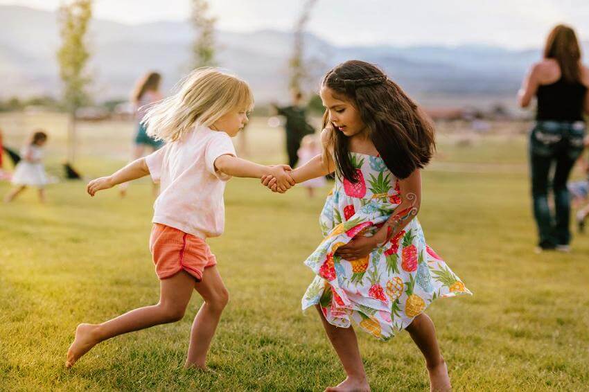 Children joyfully dancing on a grassy field.