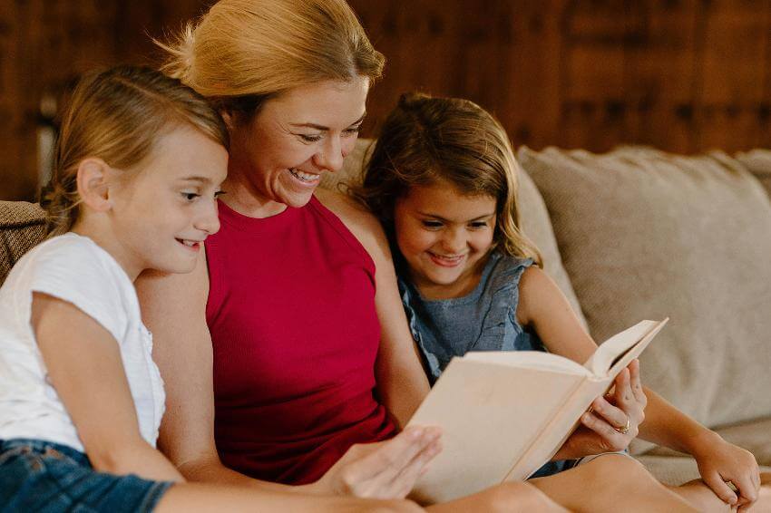 Family reading book together on cozy couch.
